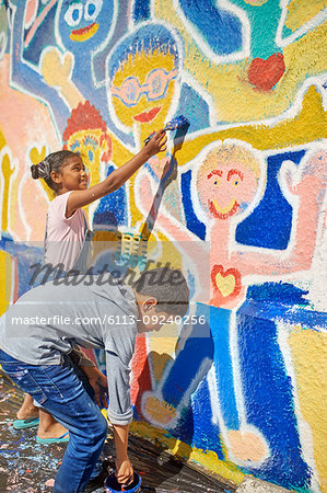 Children painting vibrant mural on sunny wall