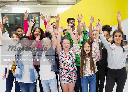 Portrait enthusiastic junior high students and teachers cheering with arms raised