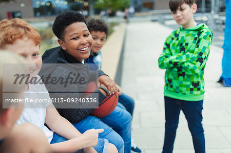 Happy tween boys with basketball in schoolyard