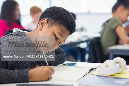 Junior high school boy student doing homework in classroom