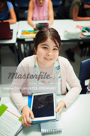 Portrait smiling, confident junior high school girl student using digital tablet in classroom