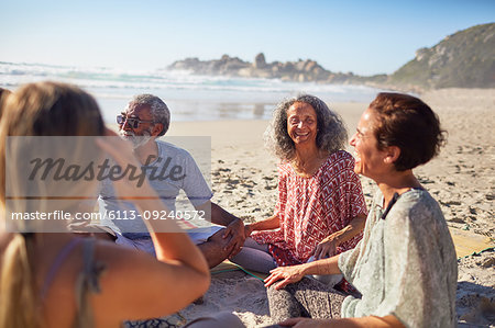 Friends sitting in circle on sunny beach during yoga retreat