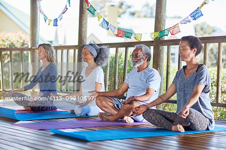 Serene people meditating in hut during yoga retreat
