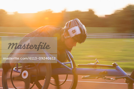 Determined young female paraplegic athlete speeding along sports track in wheelchair race