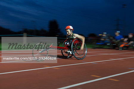 Teenage paraplegic athlete speeding along sports track in wheelchair race