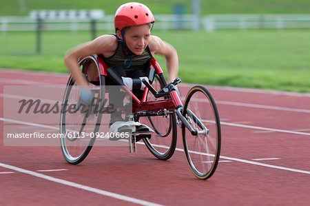 Determined, tough teenage girl paraplegic athlete speeding along sports track in wheelchair race