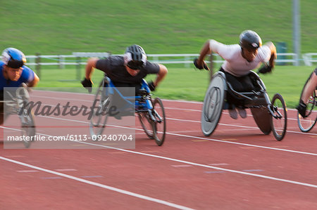 Determined paraplegic athlete speeding along sports track in wheelchair race