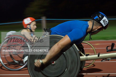 Paraplegic athletes speeding along sports track in wheelchair race at night