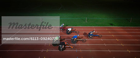 Paraplegic athletes racing along sports track in wheelchair race in night