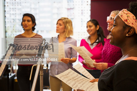 Womens choir with sheet music singing in music recording studio