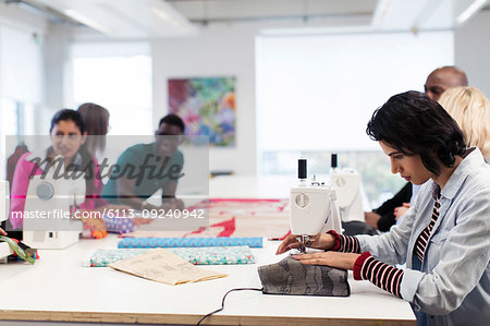 Fashion design students working at sewing machines in studio