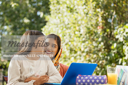 Happy mother and daughter using laptop on patio