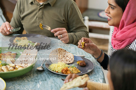 Woman in hijab eating dinner with family at table