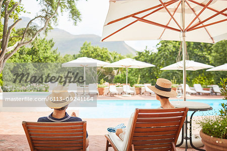 Couple relaxing on lounge chairs at sunny resort poolside