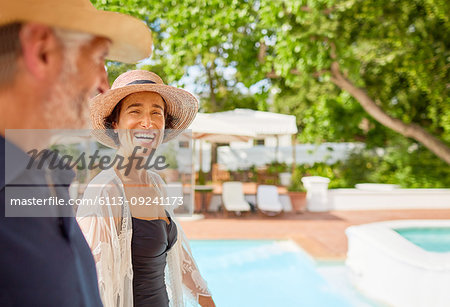 Happy mature couple at sunny resort poolside