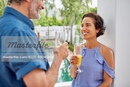 Happy mature couple drinking mimosas on hotel balcony
