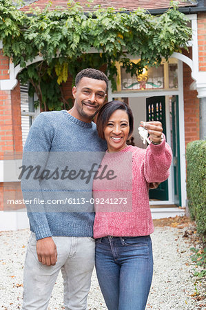 Portrait happy couple holding house keys outside new house