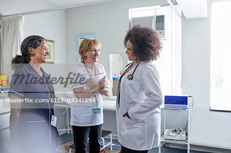 Female doctor and nurses talking in clinic examination room