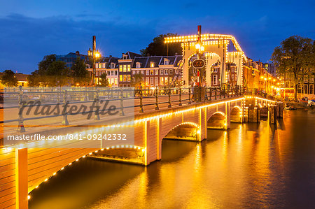 Illuminated Magere brug (Skinny Bridge) at night spanning the River Amstel, Amsterdam, North Holland, Netherlands, Europe