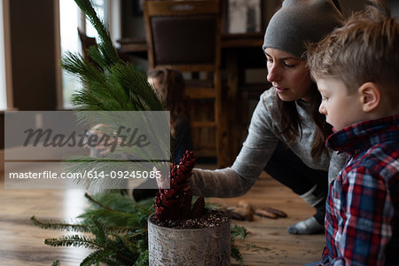 Mother and children creating potted leaf arrangement