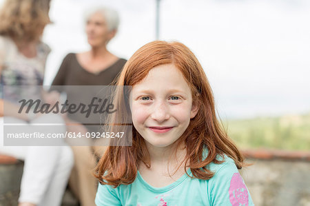 Red haired girl with mother and grandmother in background, portrait