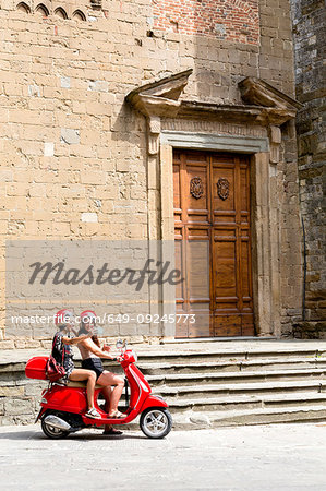 Friends taking selfie on scooter by church entrance, Città della Pieve, Umbria, Italy