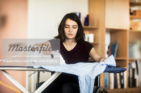 Woman in wheelchair ironing