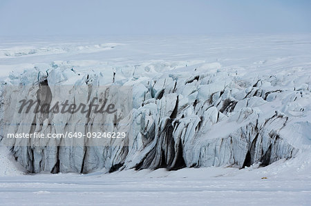 Polar bear resting in vast glacier landscape, distant view, Barents Island, Svalbard, Norway