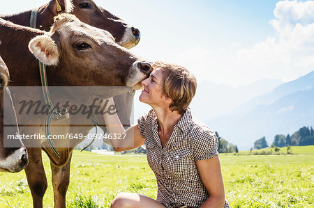 Woman bonding with herd of cows on field, Sonthofen, Bayern, Germany