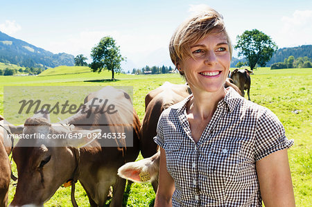 Woman bonding with herd of cows on field, Sonthofen, Bayern, Germany