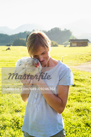 Woman carrying rooster in countryside, Sonthofen, Bayern, Germany