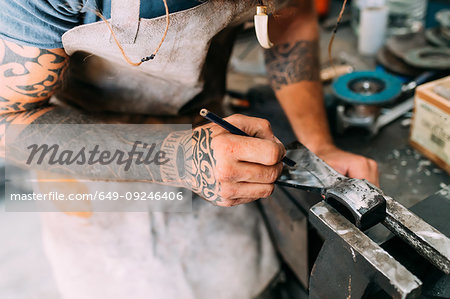 Axe maker using steel grinder in workshop