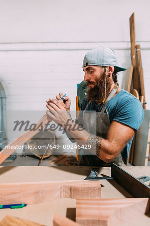 Axe maker measuring wood for axe handle in workshop