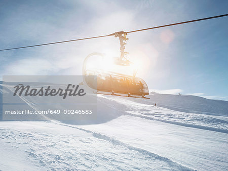 Sunlit ski lift in snow covered mountain landscape,  Alpe Ciamporino, Piemonte, Italy