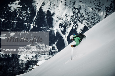 Male skier skiing down steep mountainside, Alpe-d'Huez, Rhone-Alpes, France