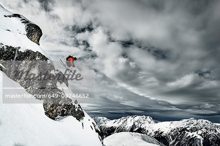 Male skier  jumping mid air from rugged mountainside, Alpe-d'Huez, Rhone-Alpes, France