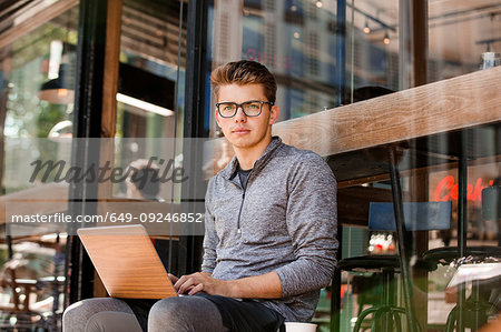 Young man using laptop at cafe, London, UK