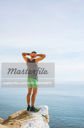 Runner looking out at sea on protruding rock, Santa Barbara, California, USA