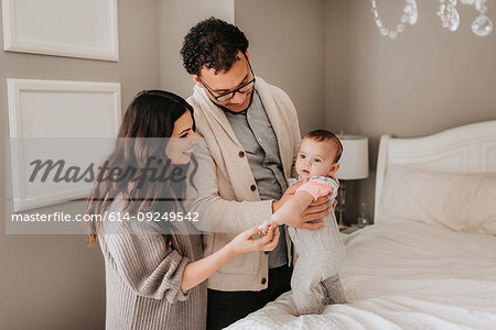 Couple with baby daughter on bed in bedroom