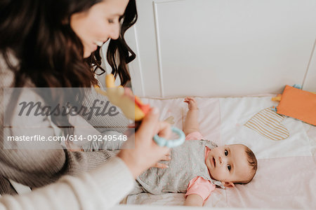 Mother putting baby daughter to bed in crib