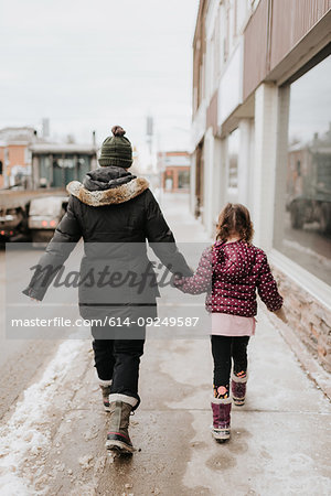 Mother and daughter walking past shop in winter