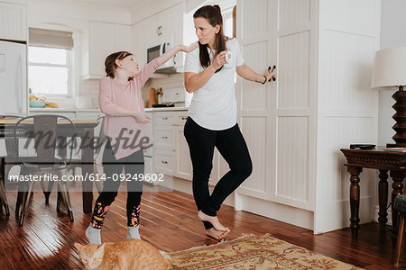 Girl extending hand to mother in kitchen