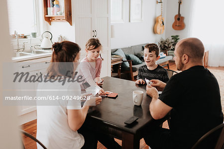 Family of four playing cards in kitchen