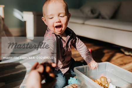 Baby boy sitting on living room floor playing with toys