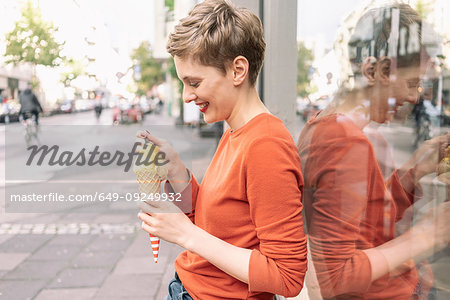 Woman eating ice cream in front of shop, Cologne, Nordrhein-Westfalen, Germany