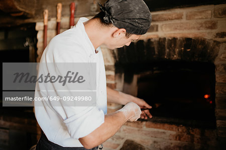 Chef placing pizza into stone oven