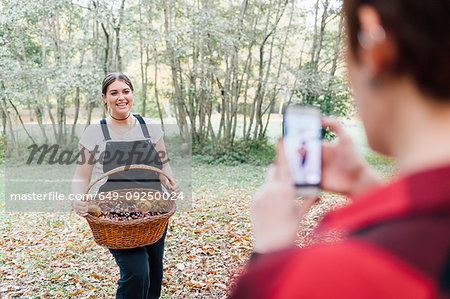 Women taking photo of chestnut collecting, Rezzago, Lombardy, Italy