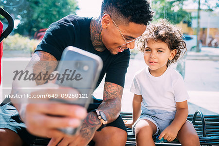 Father and son taking selfie on bench