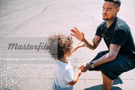 Father and son playing with confetti in park