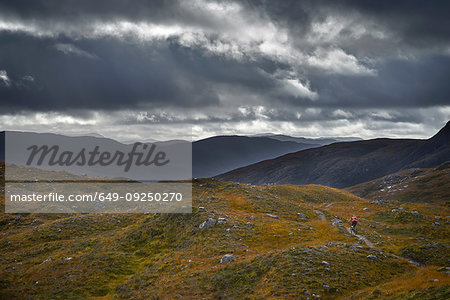 Male mountain biker biking on dirt track in mountain landscape, rear view,  Achnasheen, Scottish Highlands, Scotland